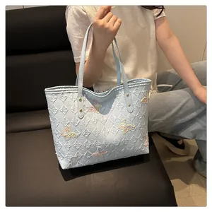 Detail of light blue tote bag with embossed textures and colorful butterfly embroidery