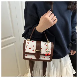White mini square handbag with cherry print, brown leather trim, and metal clasp detail
