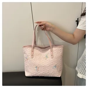 Detail of pink quilted tote bag featuring colorful sequin butterfly embroidery and long handles