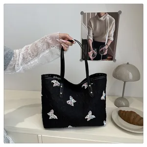 Detail of black quilted tote bag with colorful butterfly embroidery and metal rivet handles