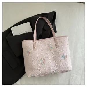 Detail of pink plaid tote bag featuring colorful butterfly embroidery and gold rivets