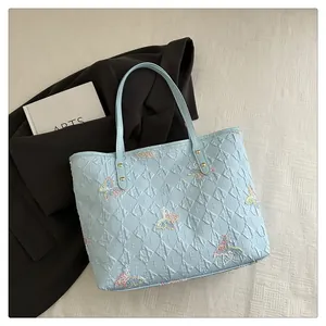 Detail of light blue tote bag with butterfly embroidery and quilted textures