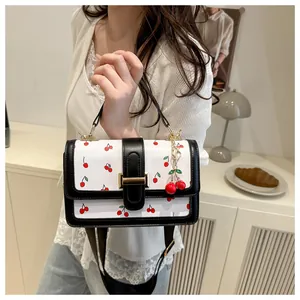 Detail of cherry print handbag with gold buckle and decorative cherry pendant