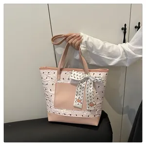 Detail of a pink and white bow-patterned tote bag with a decorative printed silk scarf