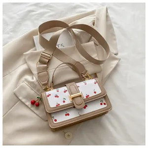Close-up of white crossbody bag with red cherry prints and stylish broad fabric strap