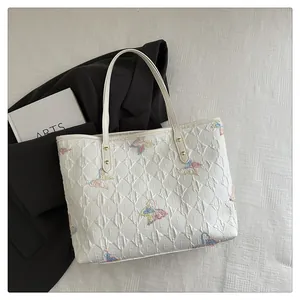 Close-up of quilted tote bag featuring colorful butterfly embroidery and gold hardware
