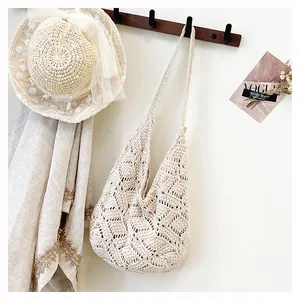 Close-up van beige gehaakte hobo-tas met bloemmotieven in een rustieke setting