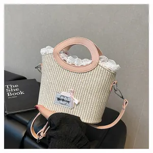 Détail du mini sac en paille avec poignée en cuir rose, dentelle et étiquette en tissu