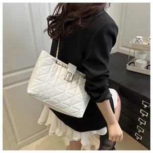 Detailed shot of white quilted tote bag with gold logo clasp and leather chain strap