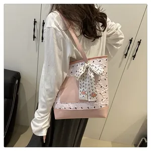 Detail of pink and white tote bag with textured patterns and a bow scarf on shoulder