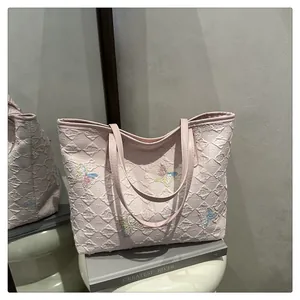Detail of pink quilted tote bag with multi-color sequin butterfly embroidery on table