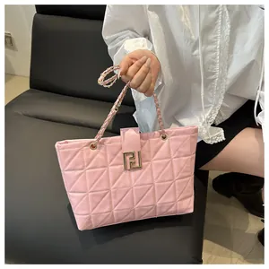 Detail of pink quilted leather tote bag featuring golden metal chain and clasp