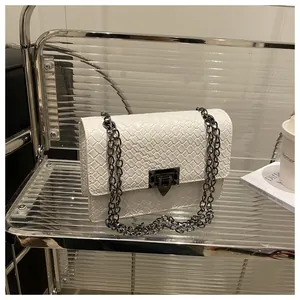 Detail of white woven texture leather on a square bag with dark grey metal chain and buckle