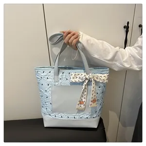Detail of light blue quilted tote bag with decorative scarf and bird pattern embroidery