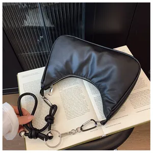 Détail du sac croissant noir avec anneau argenté et bandoulière à nœuds tressés