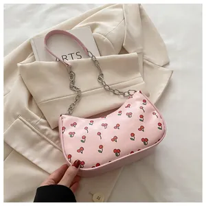 Detail of pink shoulder bag featuring red cherry prints and silver metal chain strap