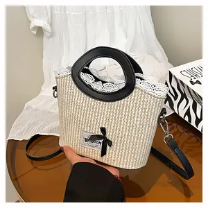 Détail du sac à main en paille avec nœud noir, bordure dentelle et poignées rondes