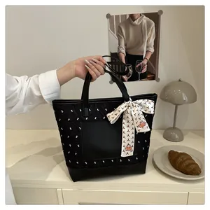 Detail of black quilted tote bag with silk scarf handle and smooth front pocket