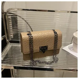 Detail of beige woven texture crossbody bag with metal chain strap on minimalist rack