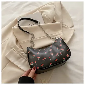 Detail of retro black underarm bag with cherry prints and silver chain strap details