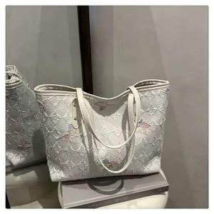 Close-up of colorful butterfly embroidery on a premium white leather tote bag surface