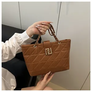 Detail of brown quilted handbag with triangle stitching and gold metal logo clasp
