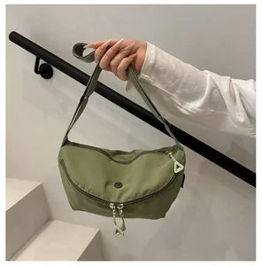 Close-up of avocado green nylon crossbody bag with metal logo and unique zipper detail