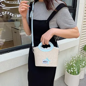 Sac seau en paille avec bordure en cuir bleu clair et détails en dentelle fine