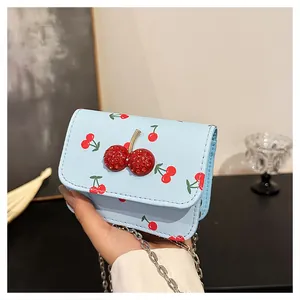 Detail of light blue crossbody bag with cherry prints and a sparkling cherry ornament