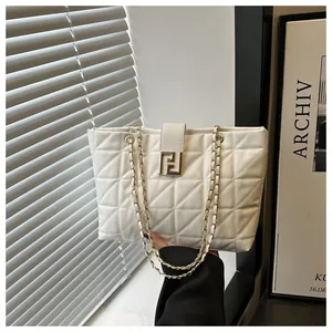 Detail of white quilted tote bag featuring a gold geometric clasp and metal chain strap