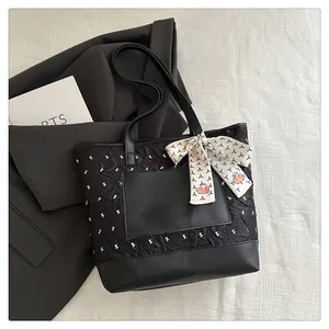 Detail of black quilted tote bag with silk scarf on a stylish blazer background