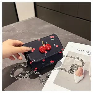 Close-up of navy blue cherry print mini bag with 3D cherry ornament and silver chain