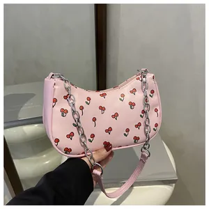 Detail of pink cherry pattern handbag with chunky gold chain strap and leather handle