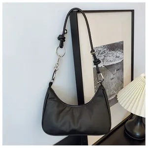 Détail du sac bandoulière demi-lune noir avec nœuds décoratifs et ferrures argentées