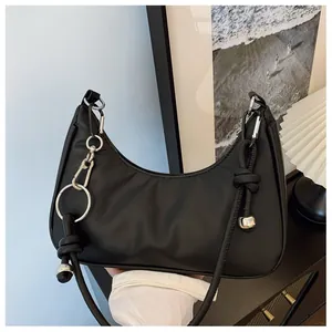 Détail du sac hobo noir avec chaîne en métal argenté et design de nœud moderne
