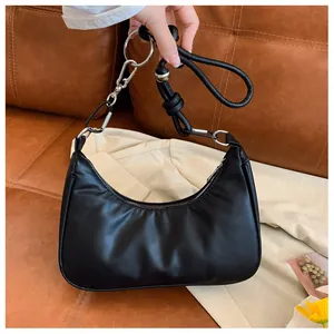 Détail du sac sous le bras noir avec bandoulière en corde tressée et boucles en métal