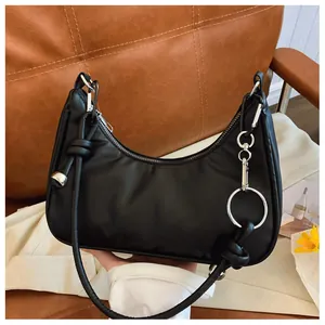 Détails du sac demi-lune en nylon noir avec finitions argentées et nœuds sur la bandoulière