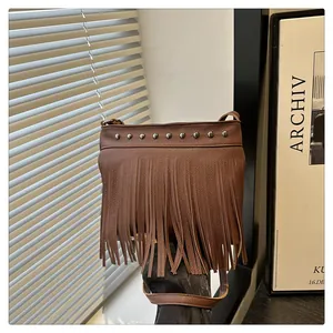 Detalle de cuero marrón con remaches plateados y flecos decorativos en el bolso de mujer