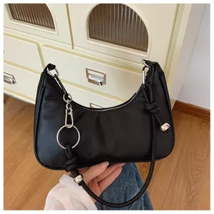 Détail d'un sac demi-lune noir avec bandoulière à nœuds et boucle métallique argentée