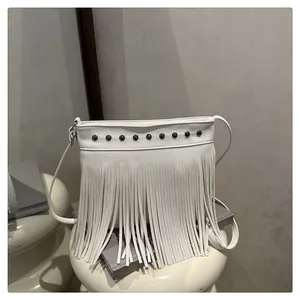 Detalle de bolso blanco de cuero con remaches metálicos y flecos decorativos