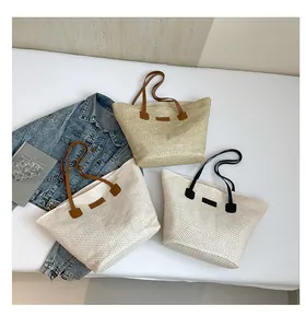 Close-up of woven straw tote bags in three colors with leather handles on white background