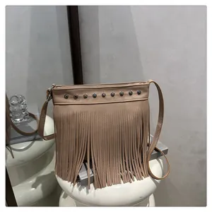 Detalle de bolso de lujo caqui con flecos, remaches metálicos y textura de cuero granulado
