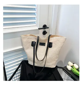 Detailed texture of beige woven straw tote bag with black leather straps and fashion patch