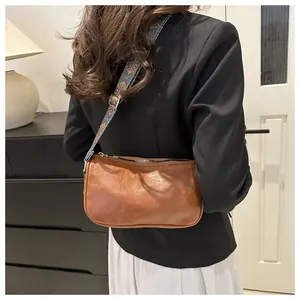 Details einer braunen Vintage-Umhängetasche mit bedrucktem Schultergurt am Modell