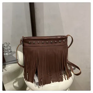 Detalle del bolso bohemio de cuero marrón oscuro con flecos y remaches de plata en soporte