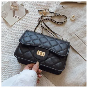 Detail of black quilted crossbody bag with golden twist lock and chain strap on fabric