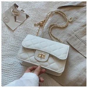 Detailed view of white quilted crossbody bag with gold chain strap and twist lock