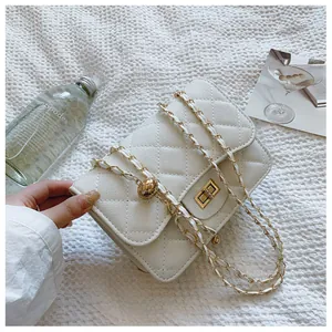 Detailed close-up of white quilted leather chain bag with golden hardware and lock