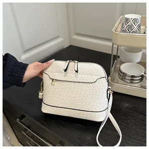 Macro detail of white woven texture shell bag with gold hardware and dual zippers