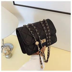 Detail of black quilted chain bag with gold metal ball adjuster and twist lock